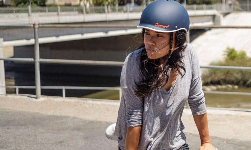 Gloria wearing a Thousand helmet in front of a bridge