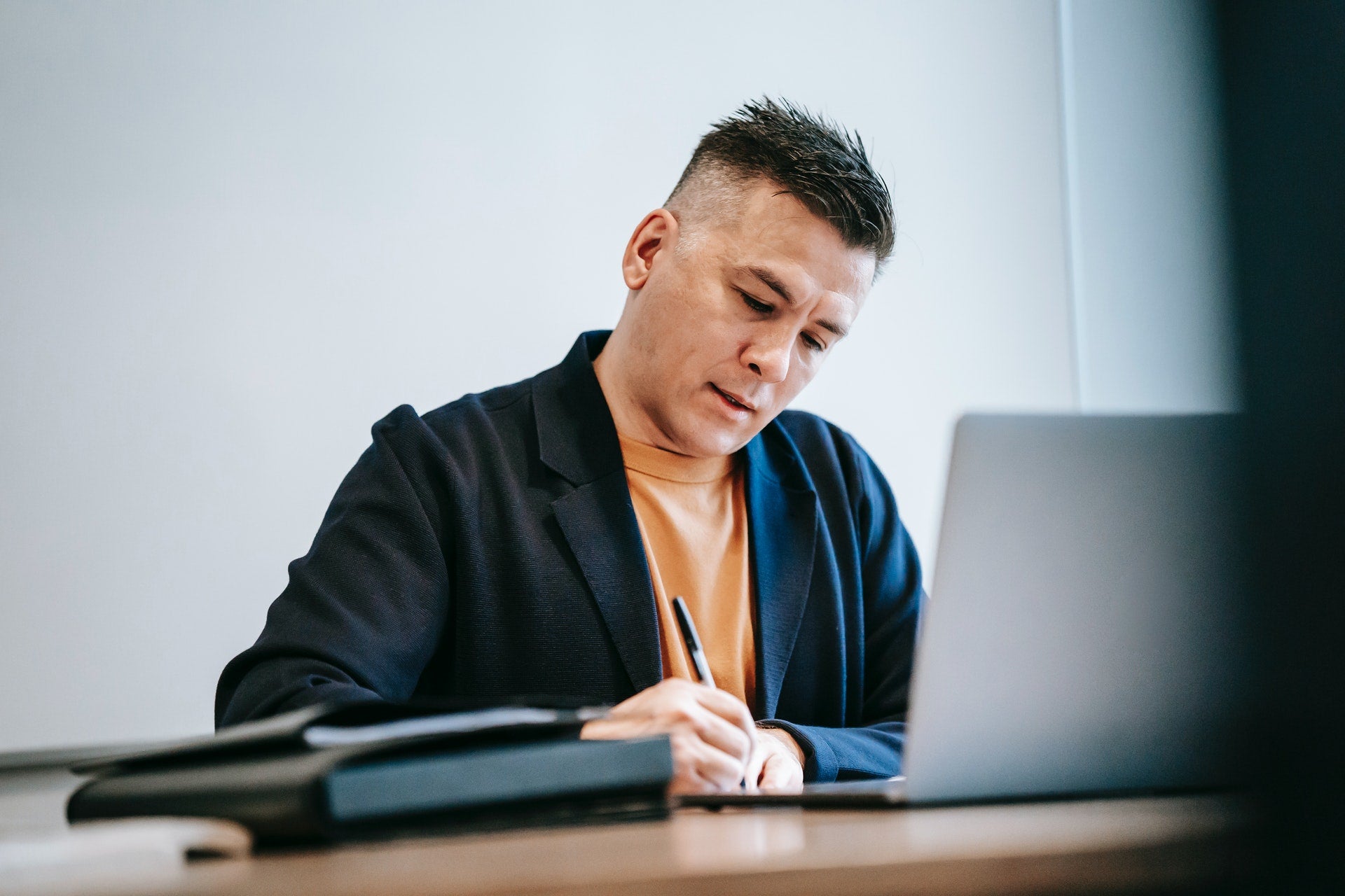 Man sitting at desk with computer writing with pen: opening an online store