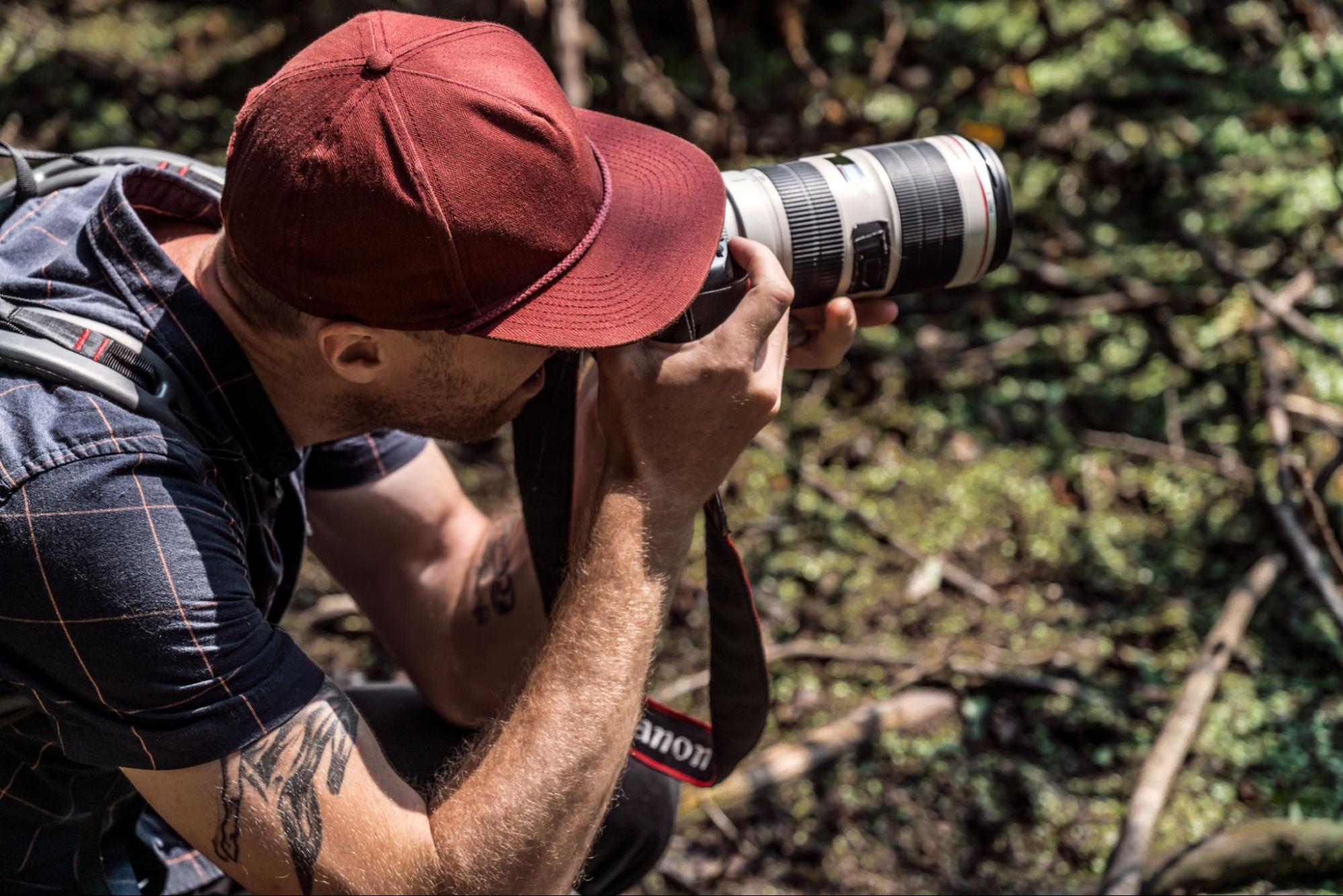 A side-view of a photographer taking pictures in nature.