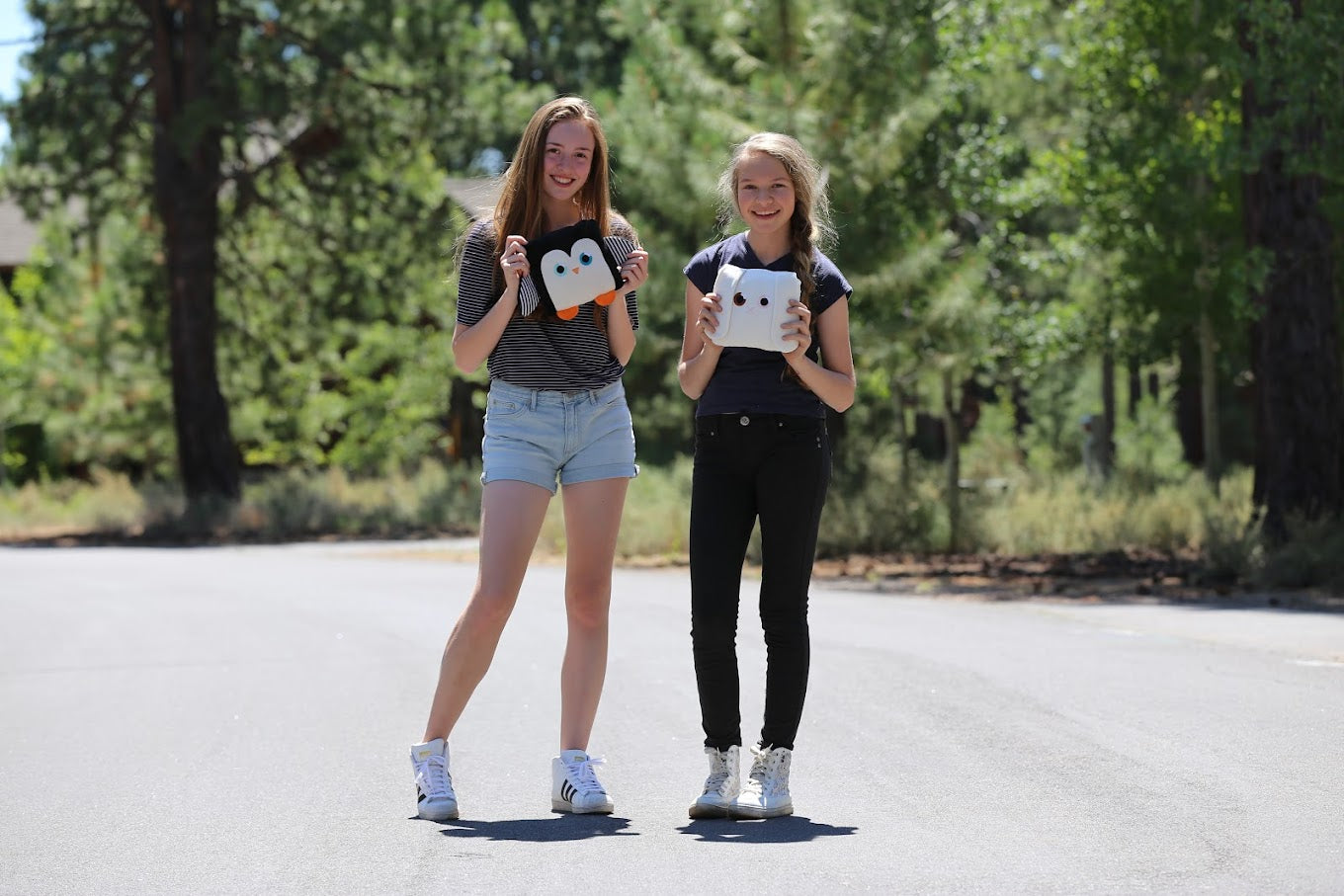 Two girls hold stuffies outside