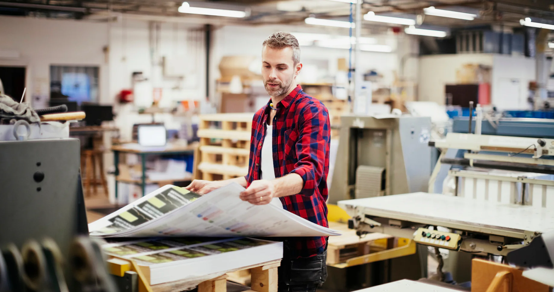 Image of a man standing at a printing station to print on demand books for his business