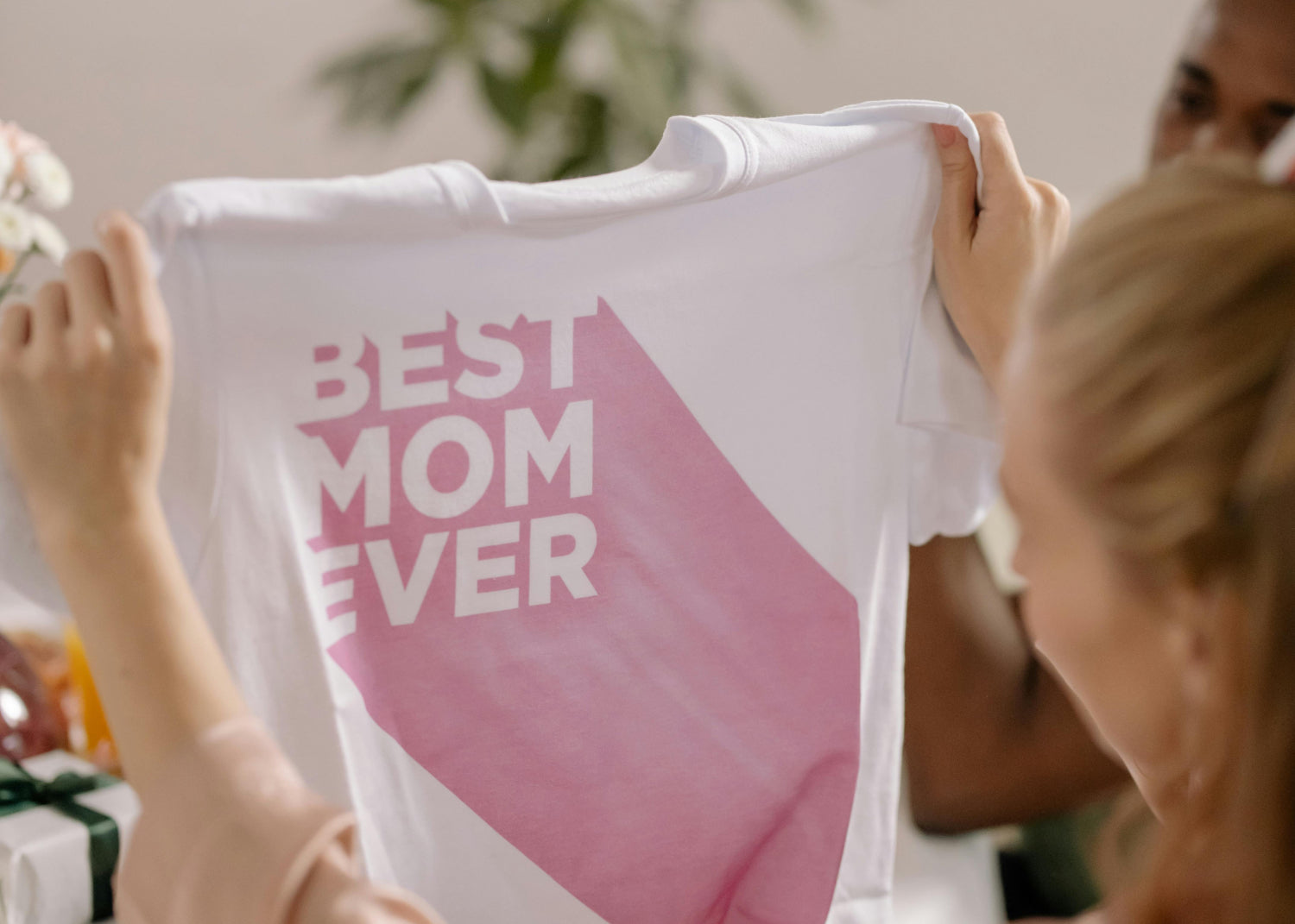 Woman holds up a printed tshirt that reads "best mom ever"