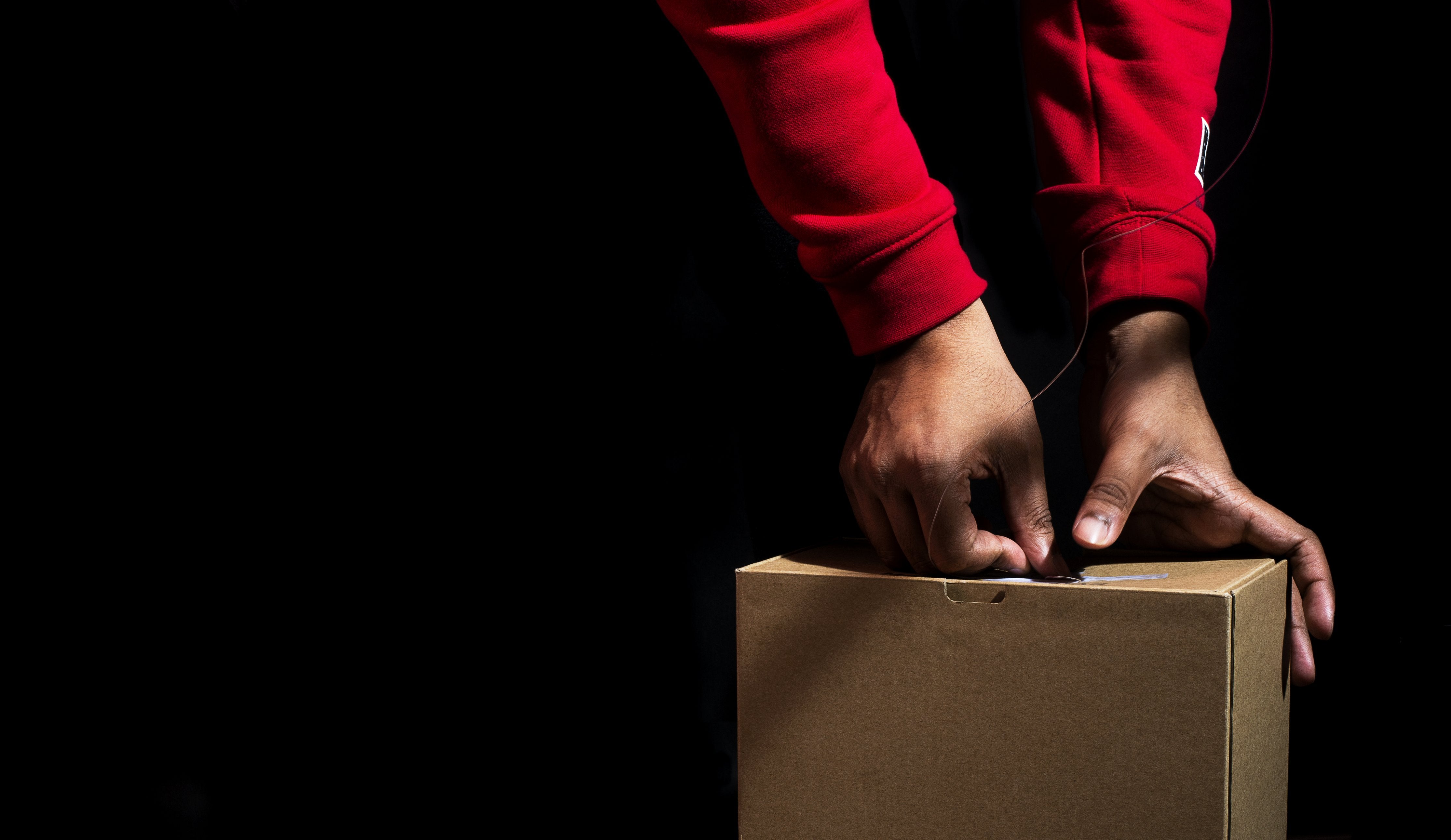 Image of a hands sealing a cardboard box with tape ready for shipping to the customer