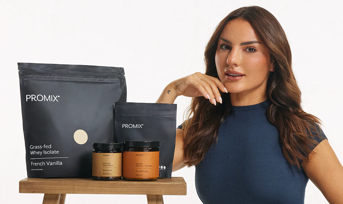 A woman in a blue shirt models a selection of Promix supplement powders, which are arranged in a stool.