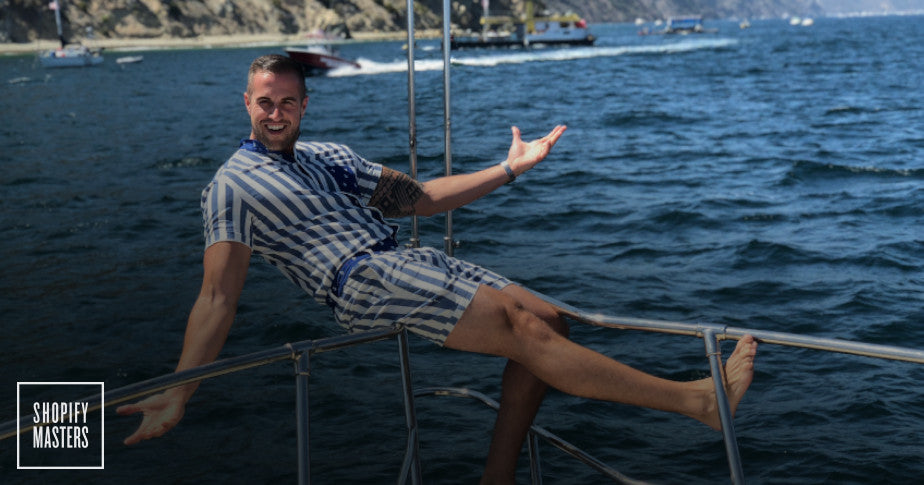 Male model wearing a Romperjack stripped romper on a boat. 