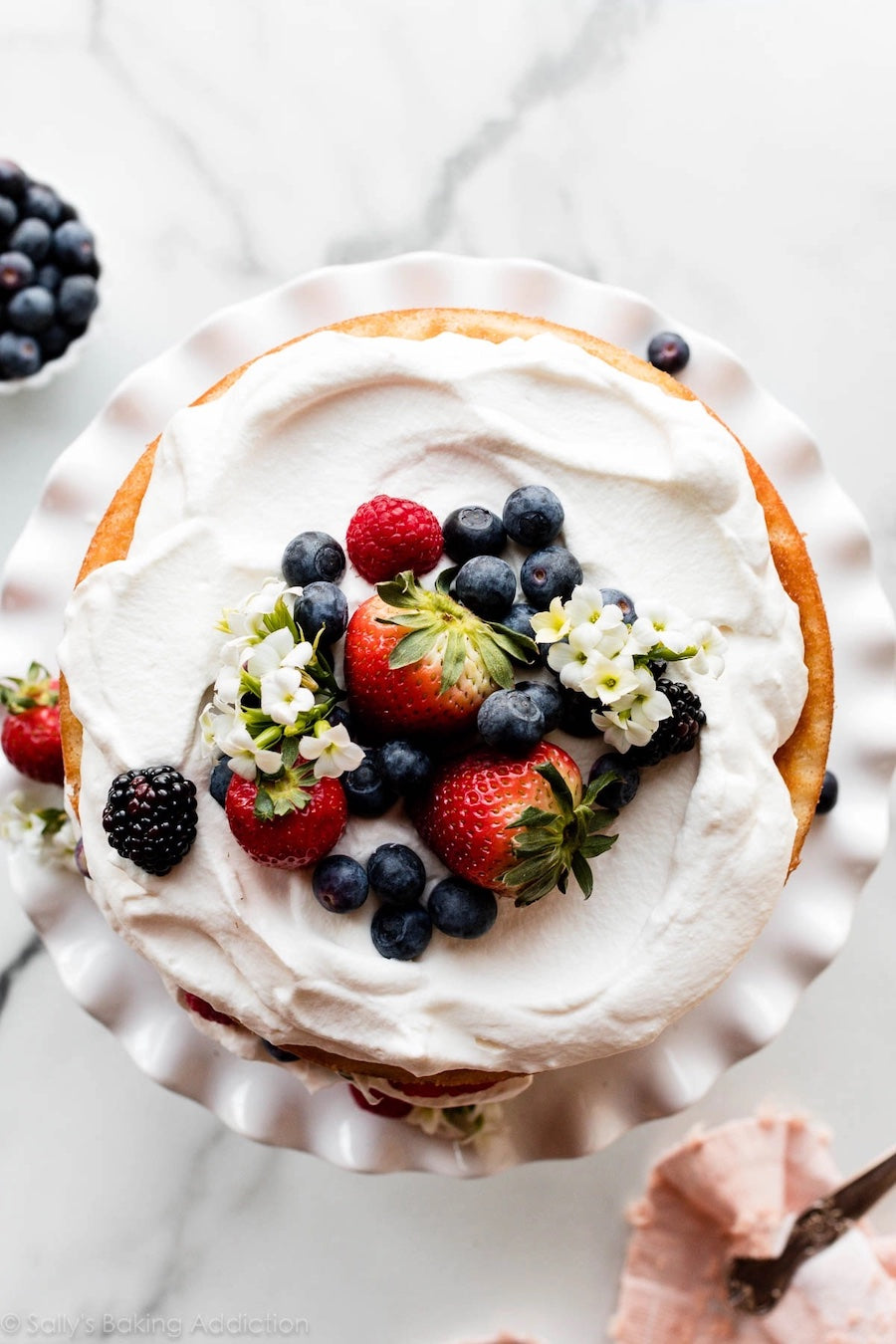 An aerial shot of a cake with white icing and mixed berries on top