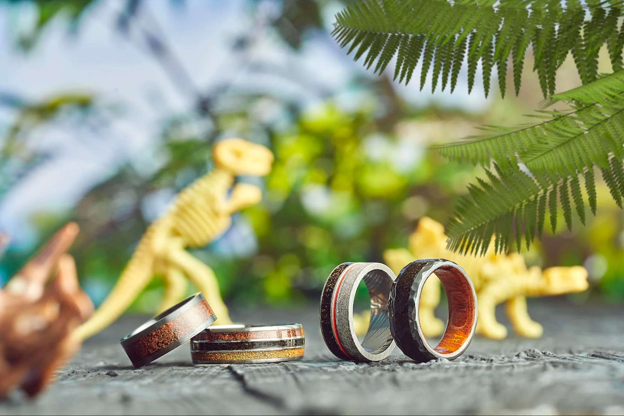 Photo of four male wedding rings against a tropical backdrop. 