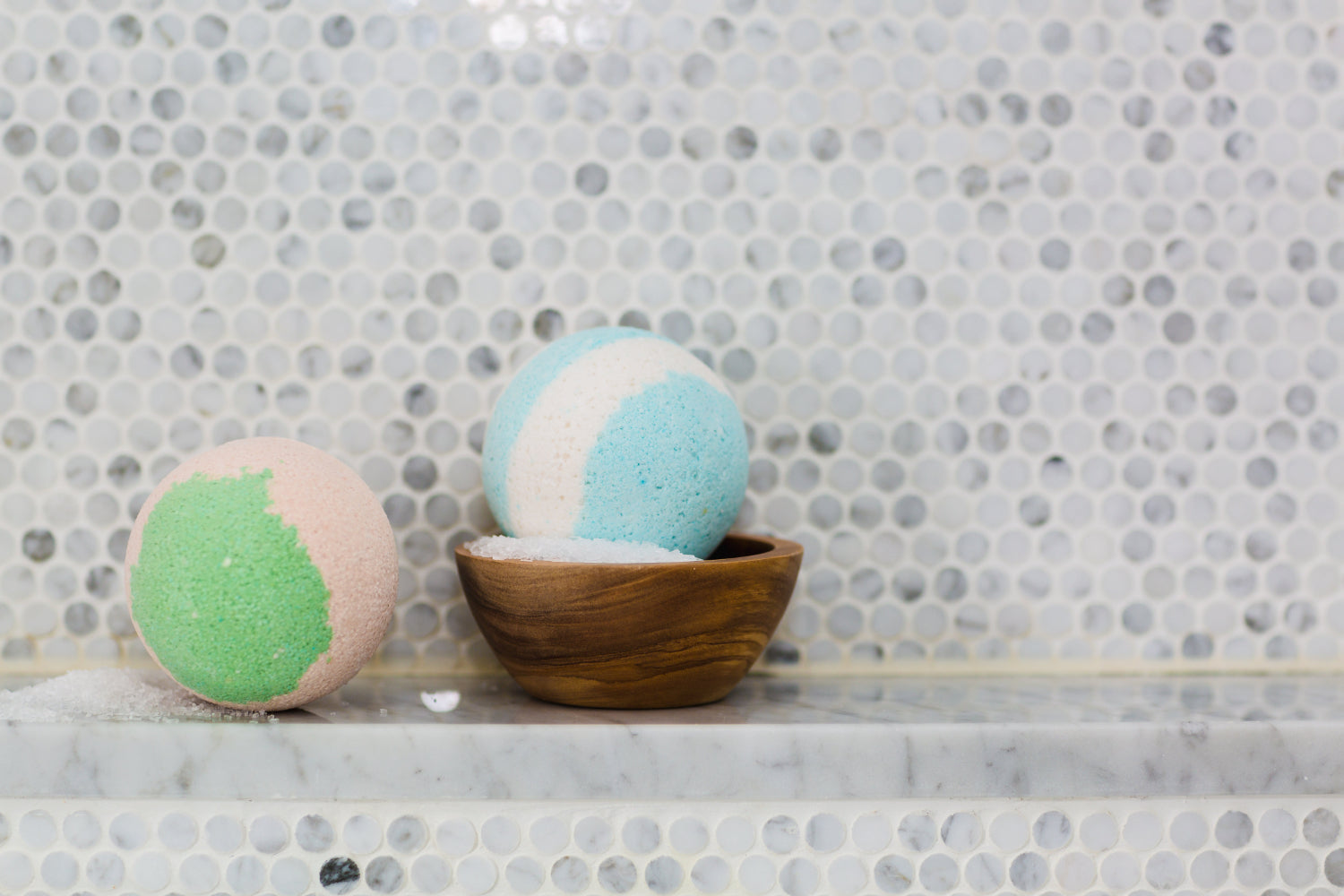 Two bath fizzies sit on the edge of a tub