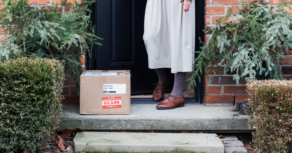 一个女人从家门口拿起一个包裹的照片