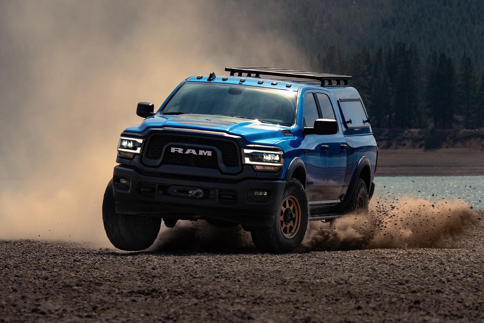 A blue Ram vehicle suited with Shock Surplus shocks and suspensions drives through the dirt. 