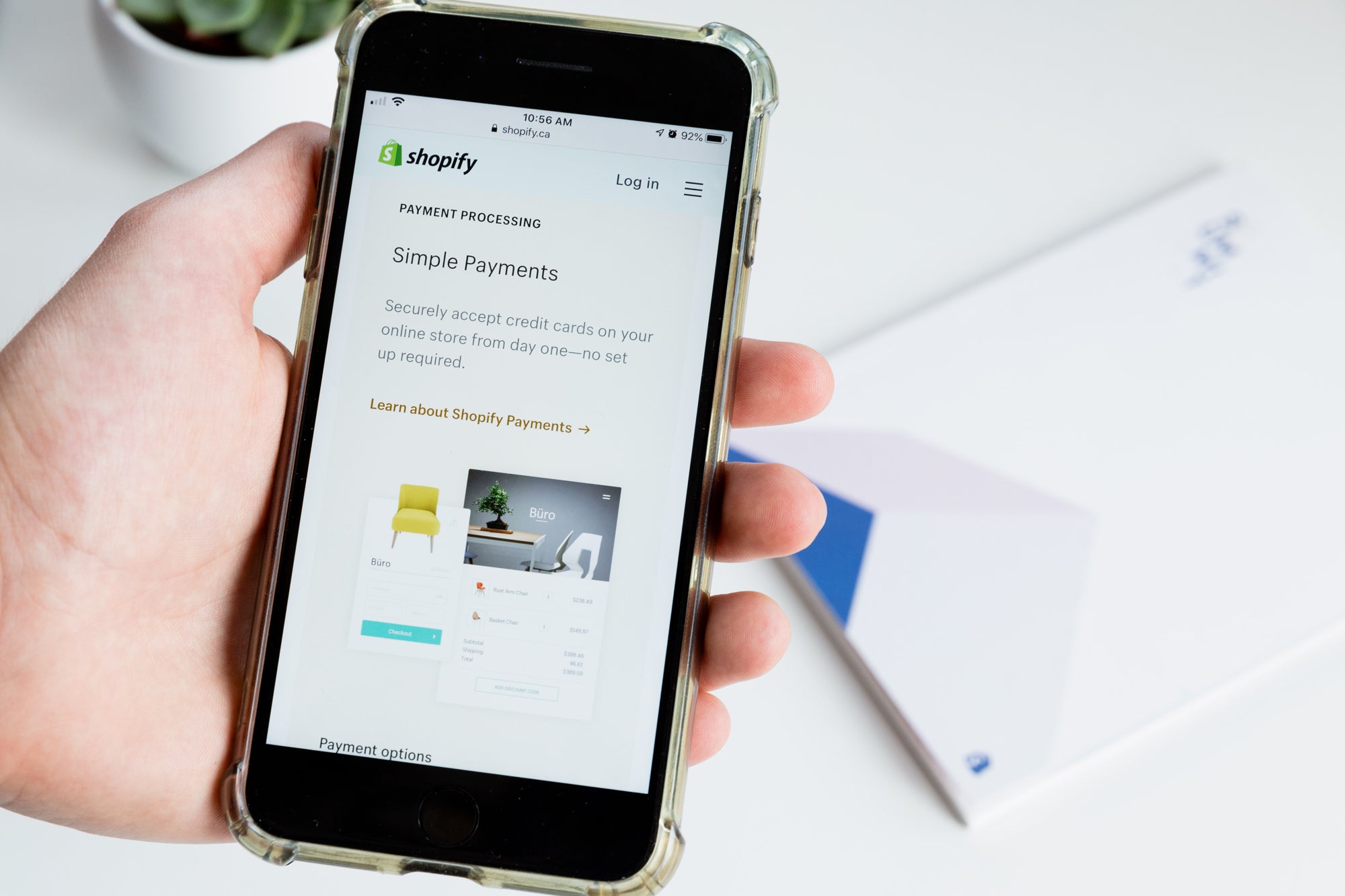 Hand holds a phone open to a screen that reads "shopify payments"