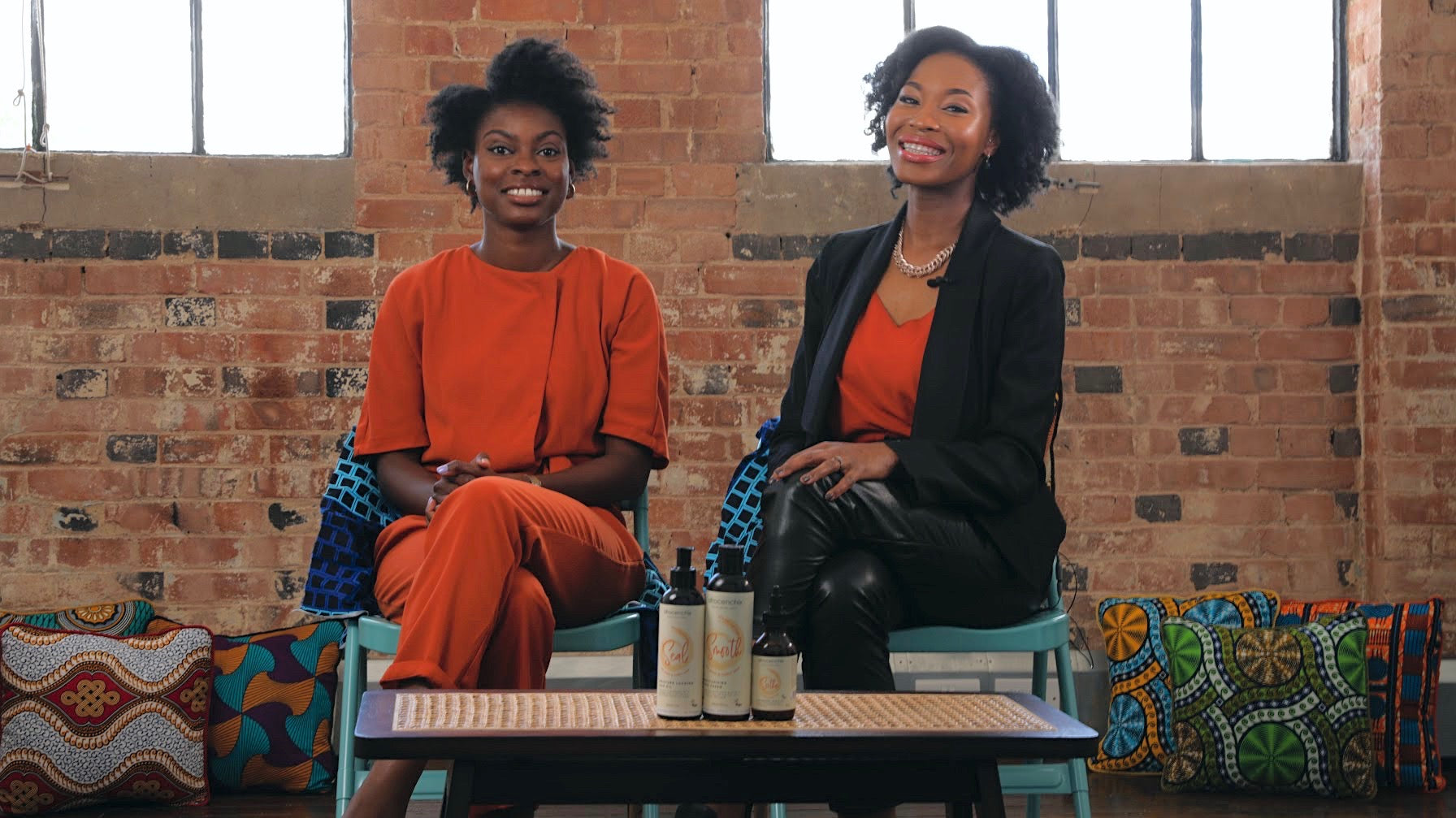 The co-founders of Afrocenchix, Joycelyn Mate and Rachael Corson sitting down with products in front of them. 