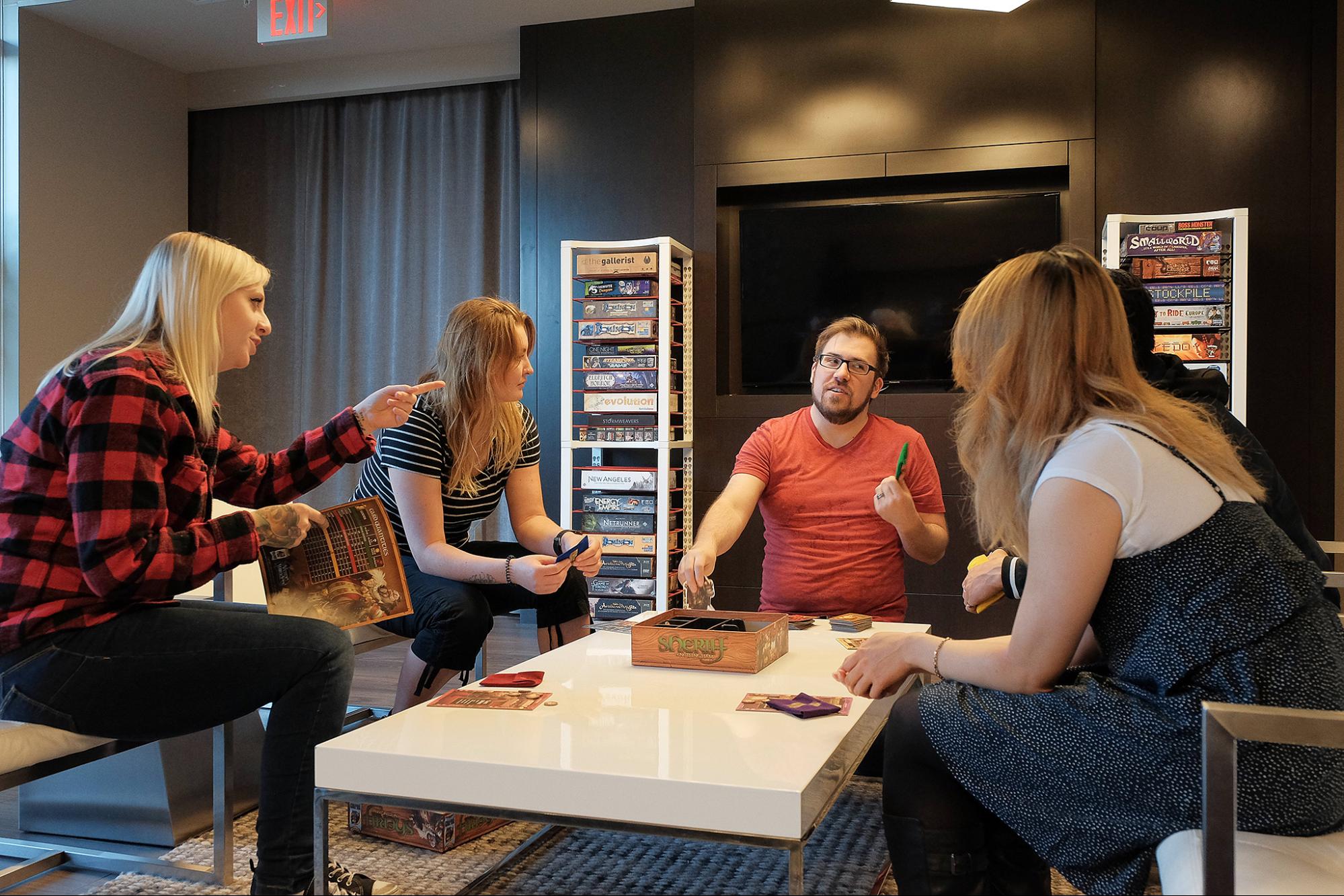 Friends playing some board games backdropped by two shelving units from BoxThrone. 