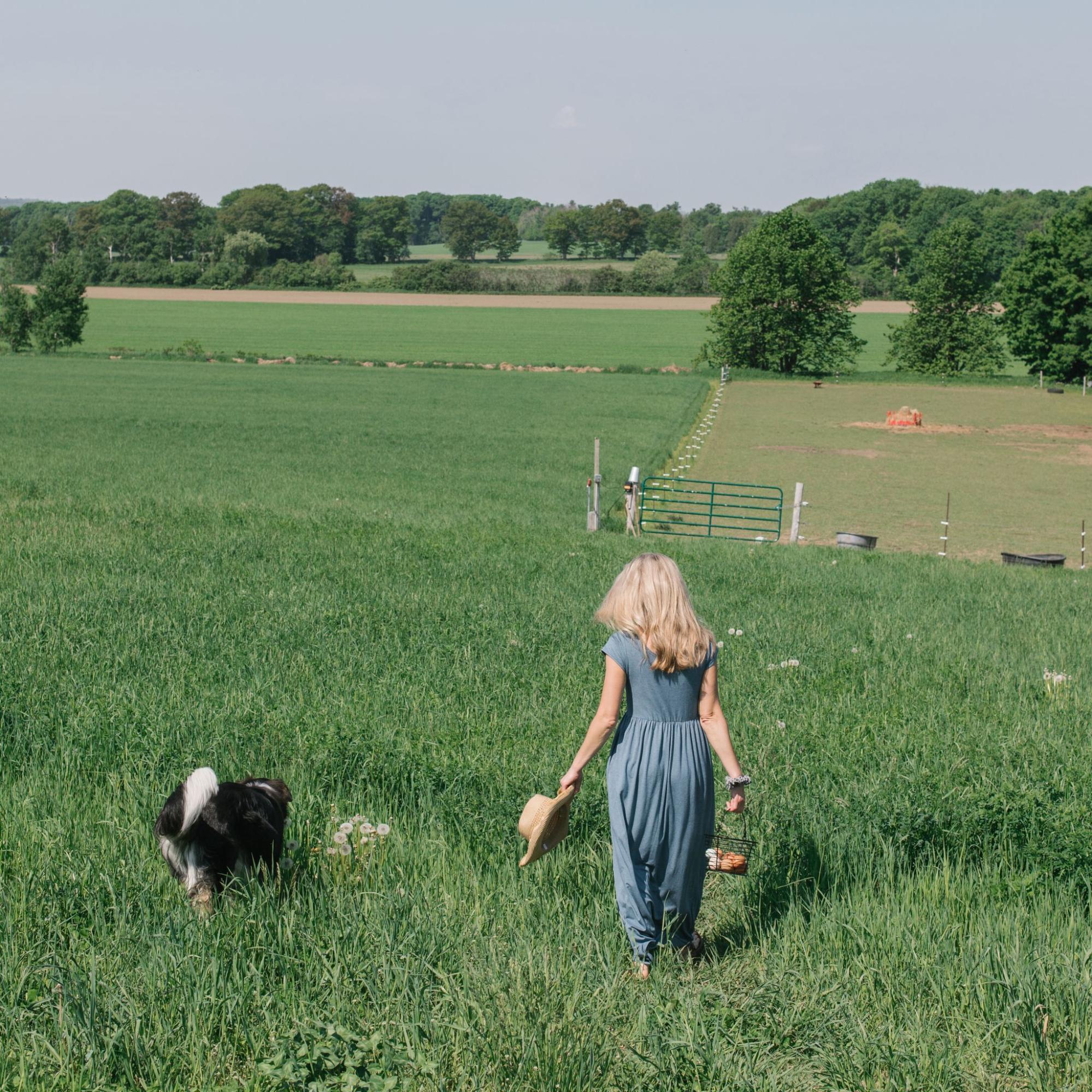 A model along with a dog in a field, wearing a blue dress from Buttercream Clothing. 