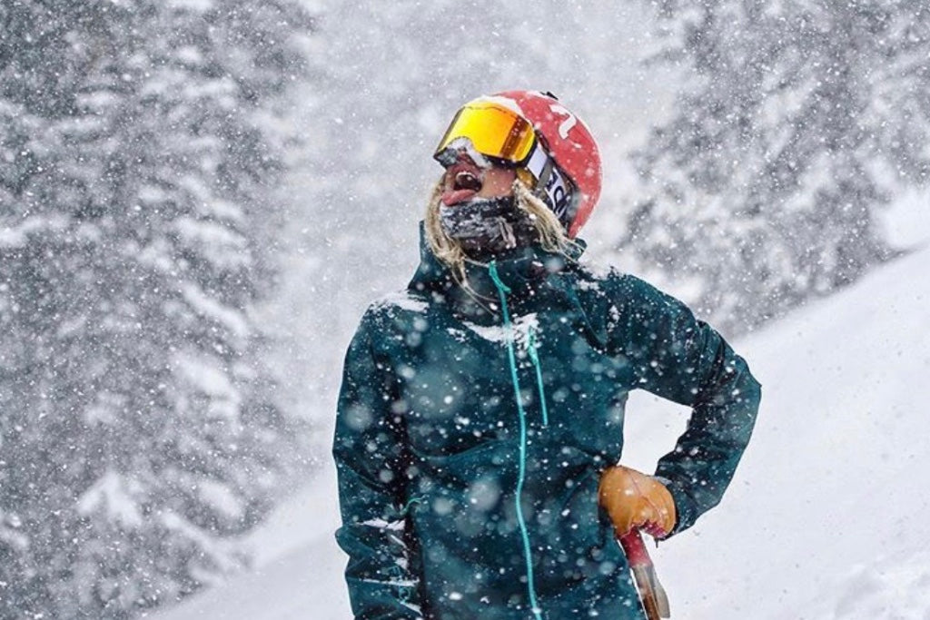 a female skier backdropped by snow hills is wearing a Glade Optics goggle.