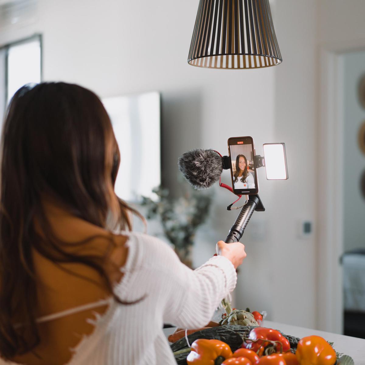 A model with a self stick, smartphone and Lume Cube lighting recording herself in a kitchen.