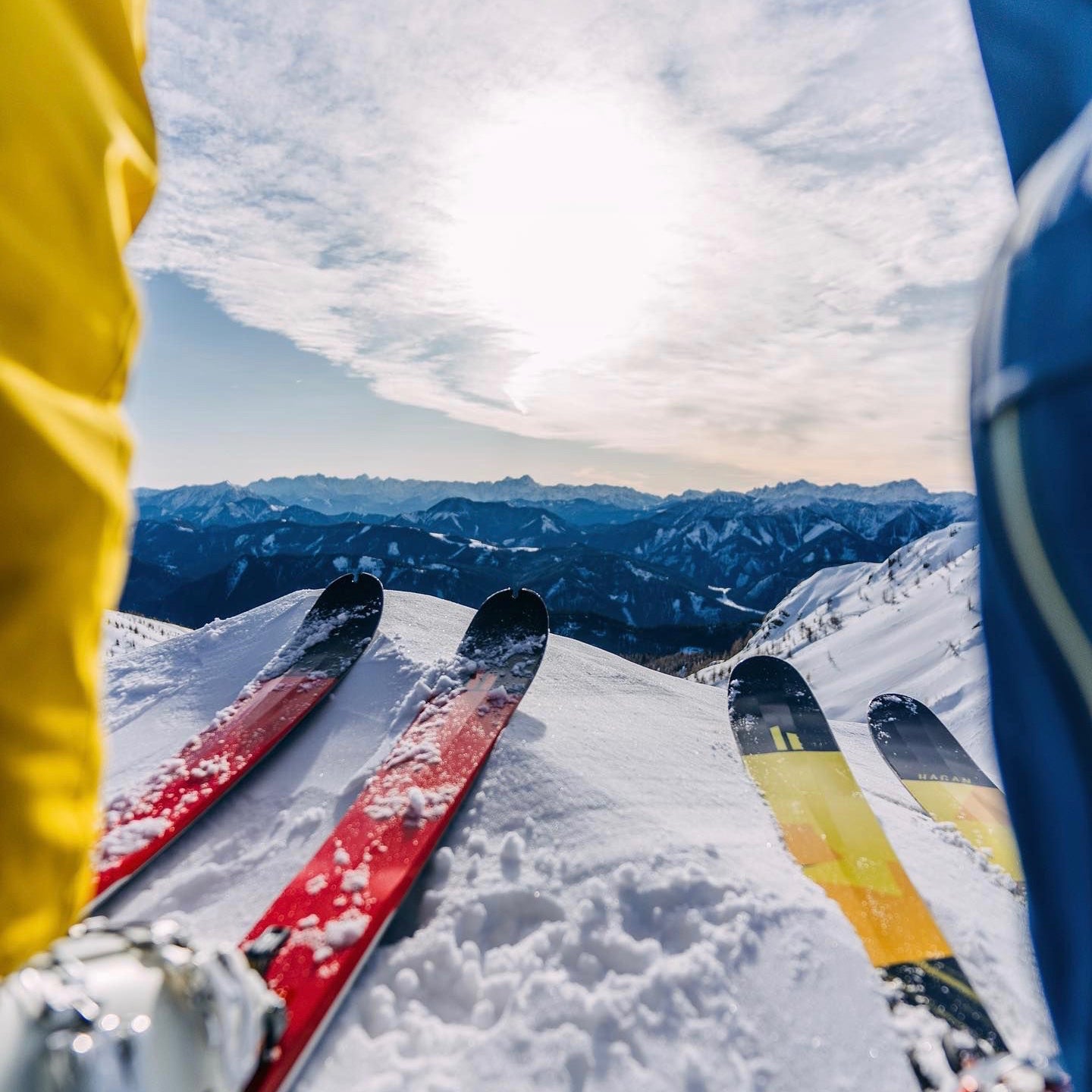 A pair of skis backdropped by snowy mountaintops. 