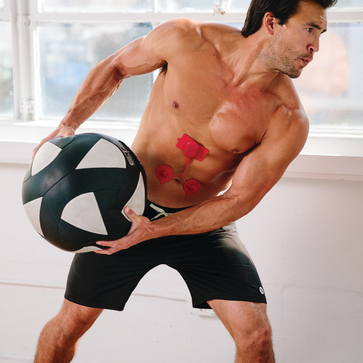 A model with an exercise hall and the PowerDot device on his abs. 