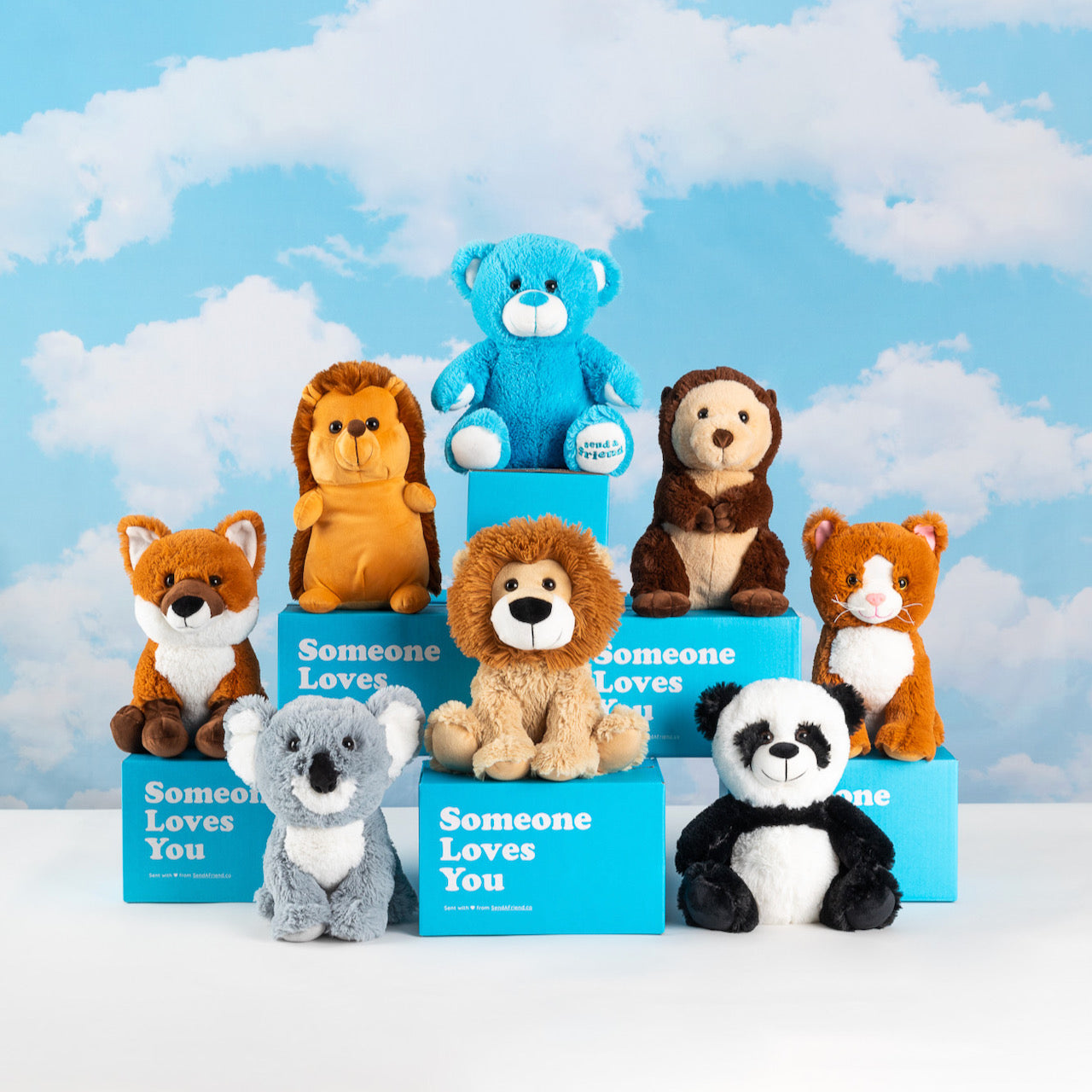 An array of stuffed animals along with blue gift boxes from SendAFriend back dropped by a background with clouds painted.