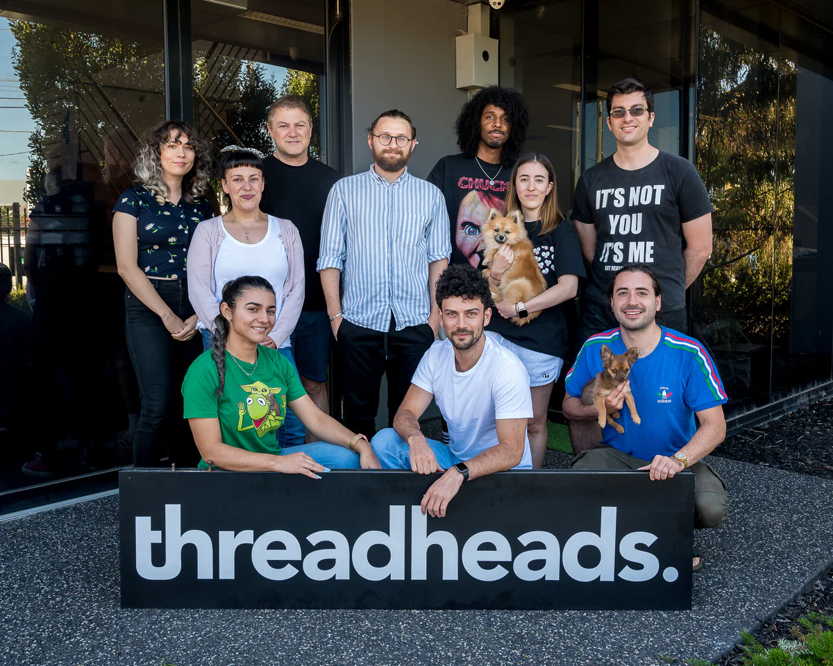 The team behind Threadheads in front of their office with a Threadheads sign in front of the group. 