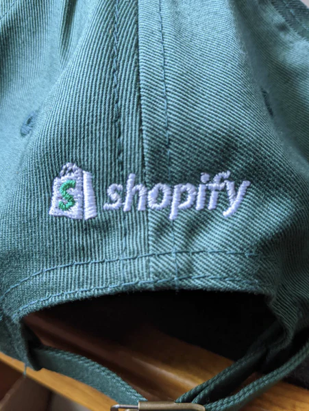 Green Shopify ball cap with white embroidered logo and and name
