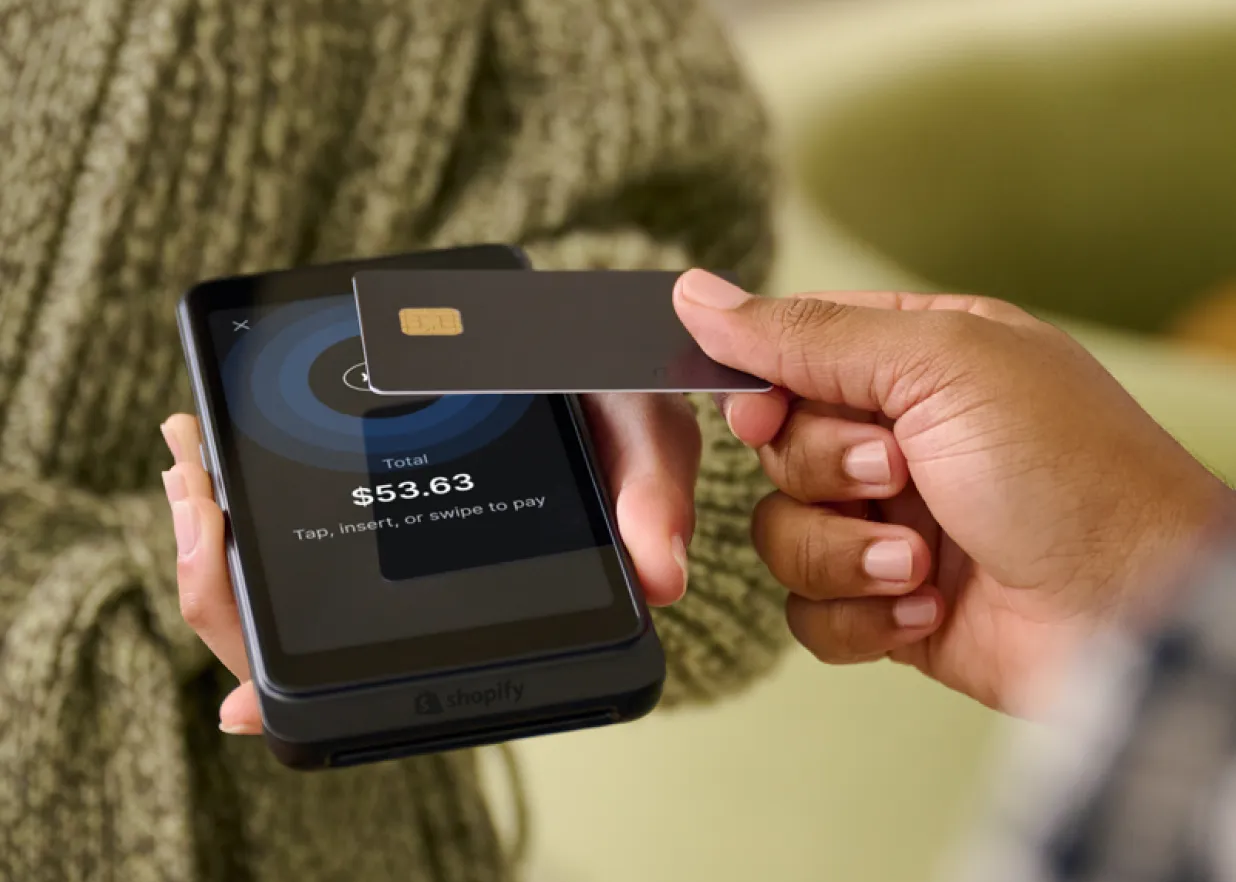 A person taps a credit card on a Shopify POS device