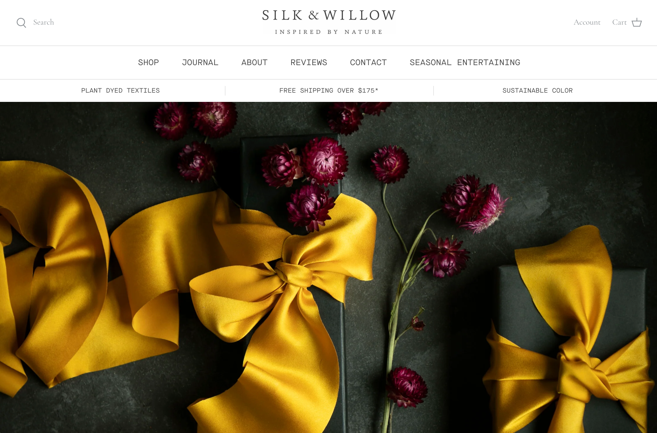Silk &amp; Willow电商网站主页，展示着紫红色花朵和用黄色丝带装饰的墨绿色精美包装盒
