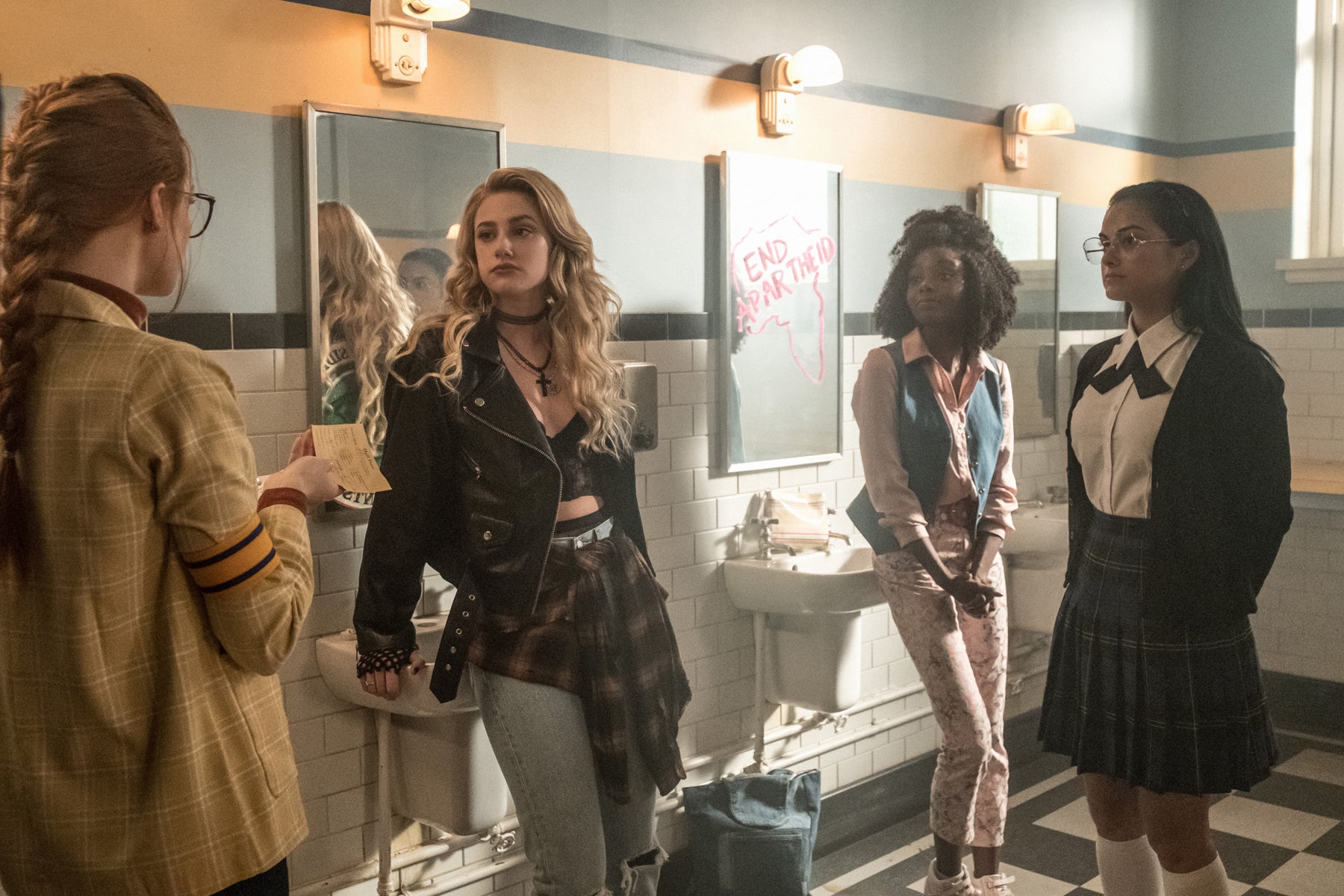 In a flashback scene, young versions of Penelope Blossom, Alice Cooper, Sierra McCoy, and Hermione Lodge stand in the bathroom at Riverdale High.
