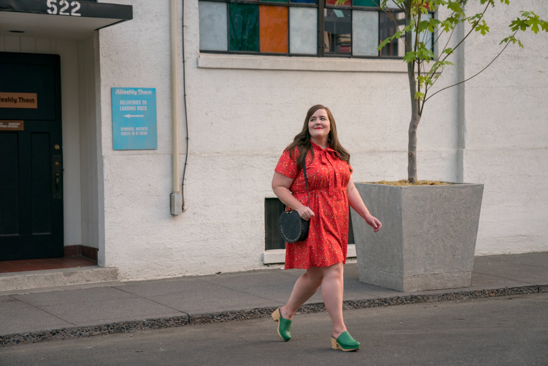 Annie smiles as she walks confidently in a red dress. 