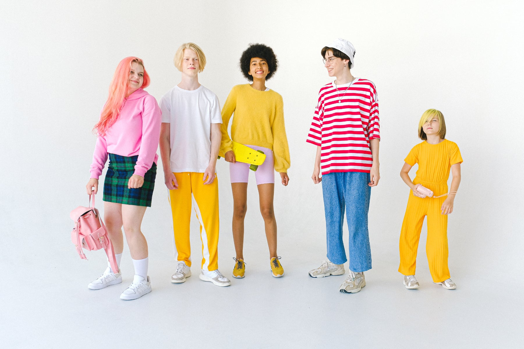 A group of kids and teens stand in a row wearing colorful clothing
