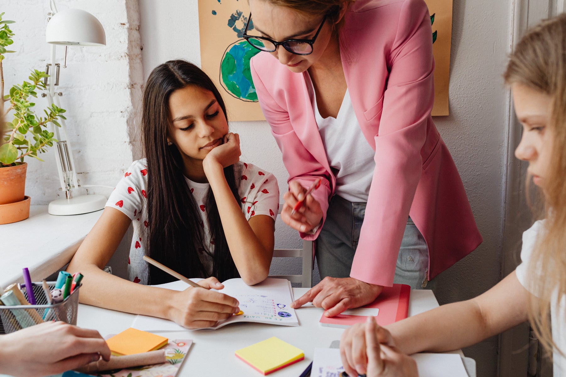 A group of children get help from an adult with some school work