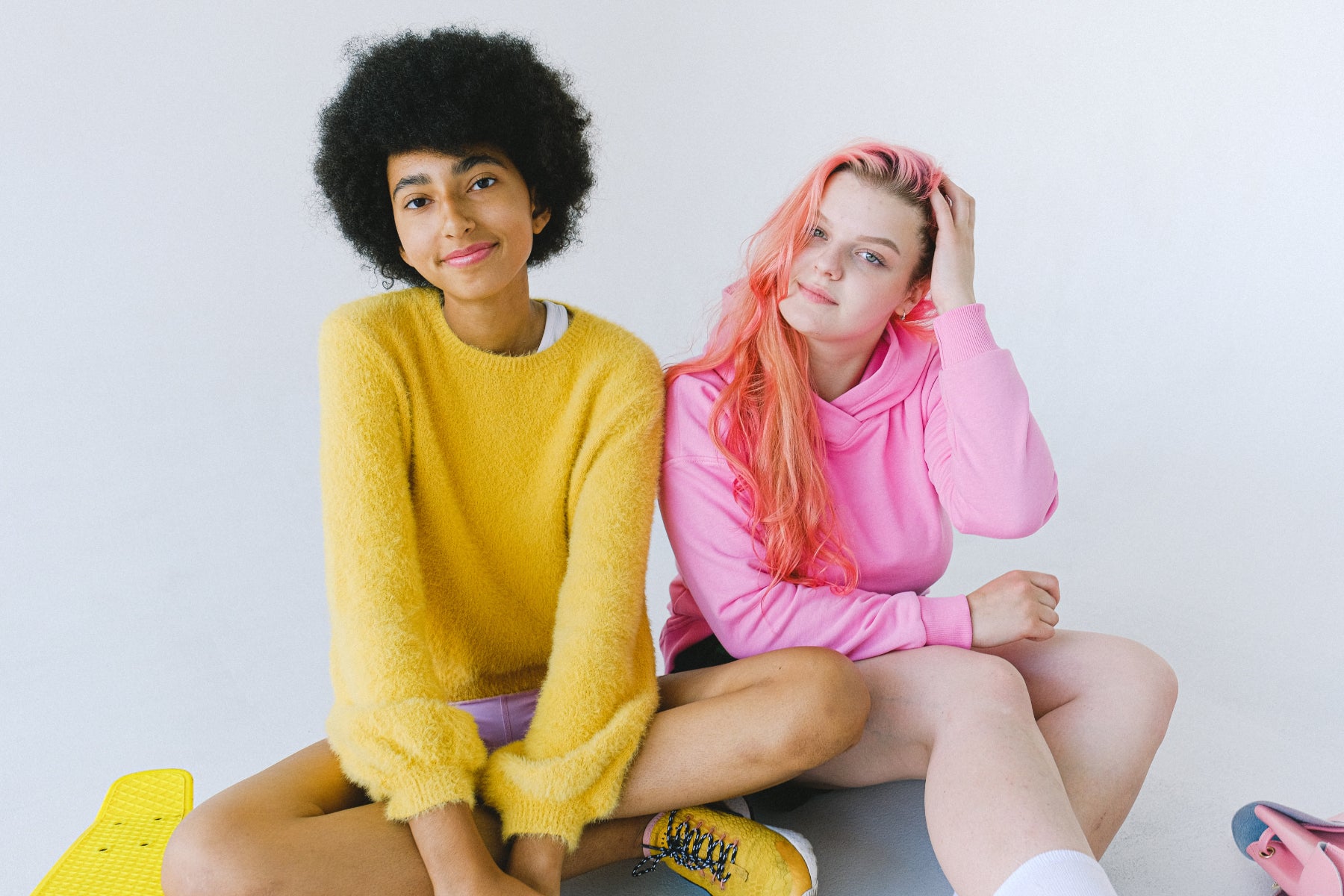 Two teenagers sit on the floor looking at the camera