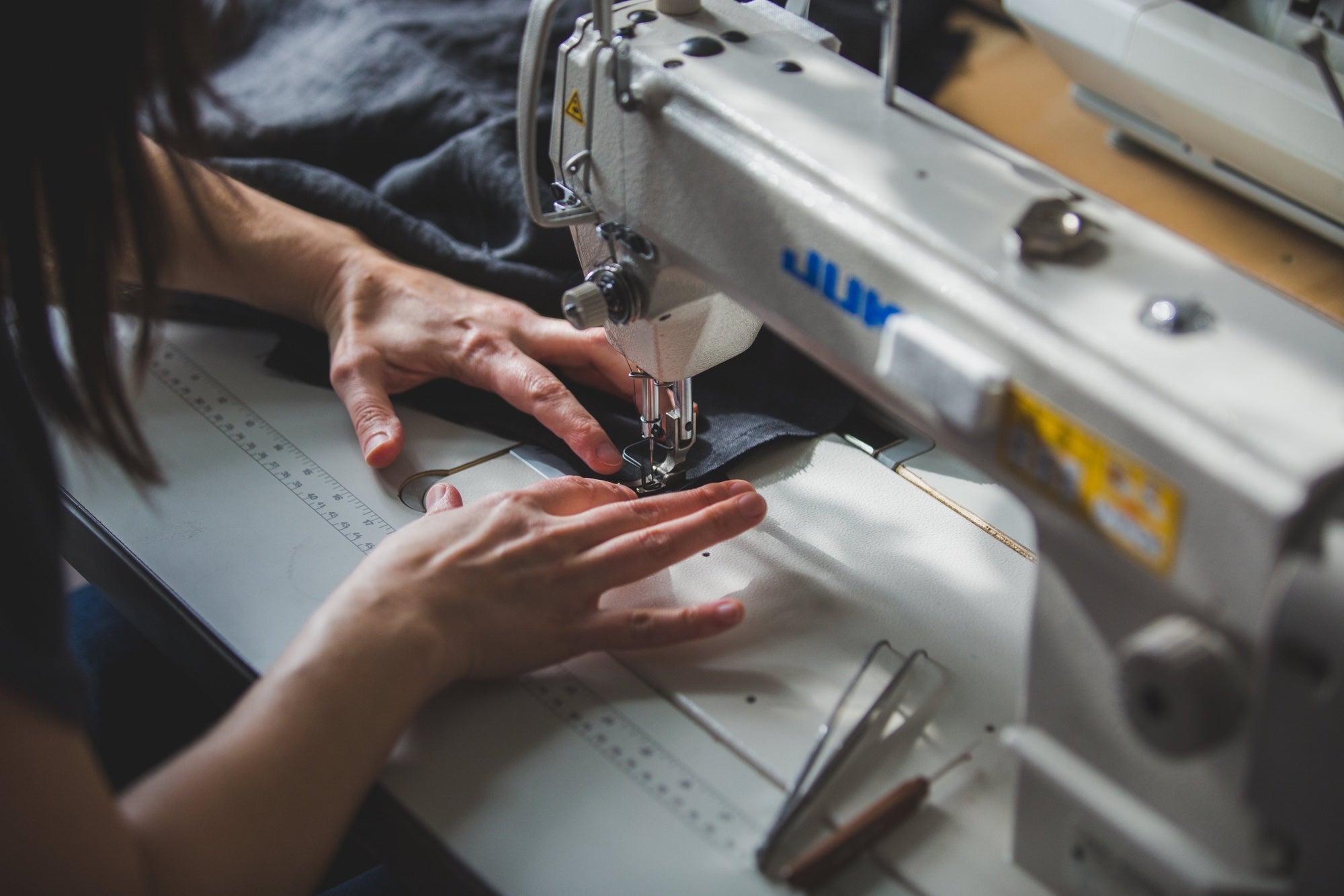 Close up of a person's hands sewing garments on a Juki Sewing machine