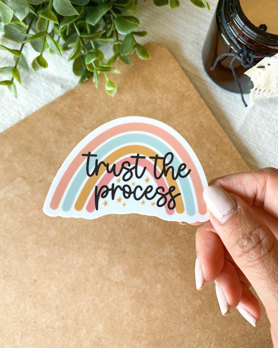a sticker of a rainbow behind the words “trust the process.”