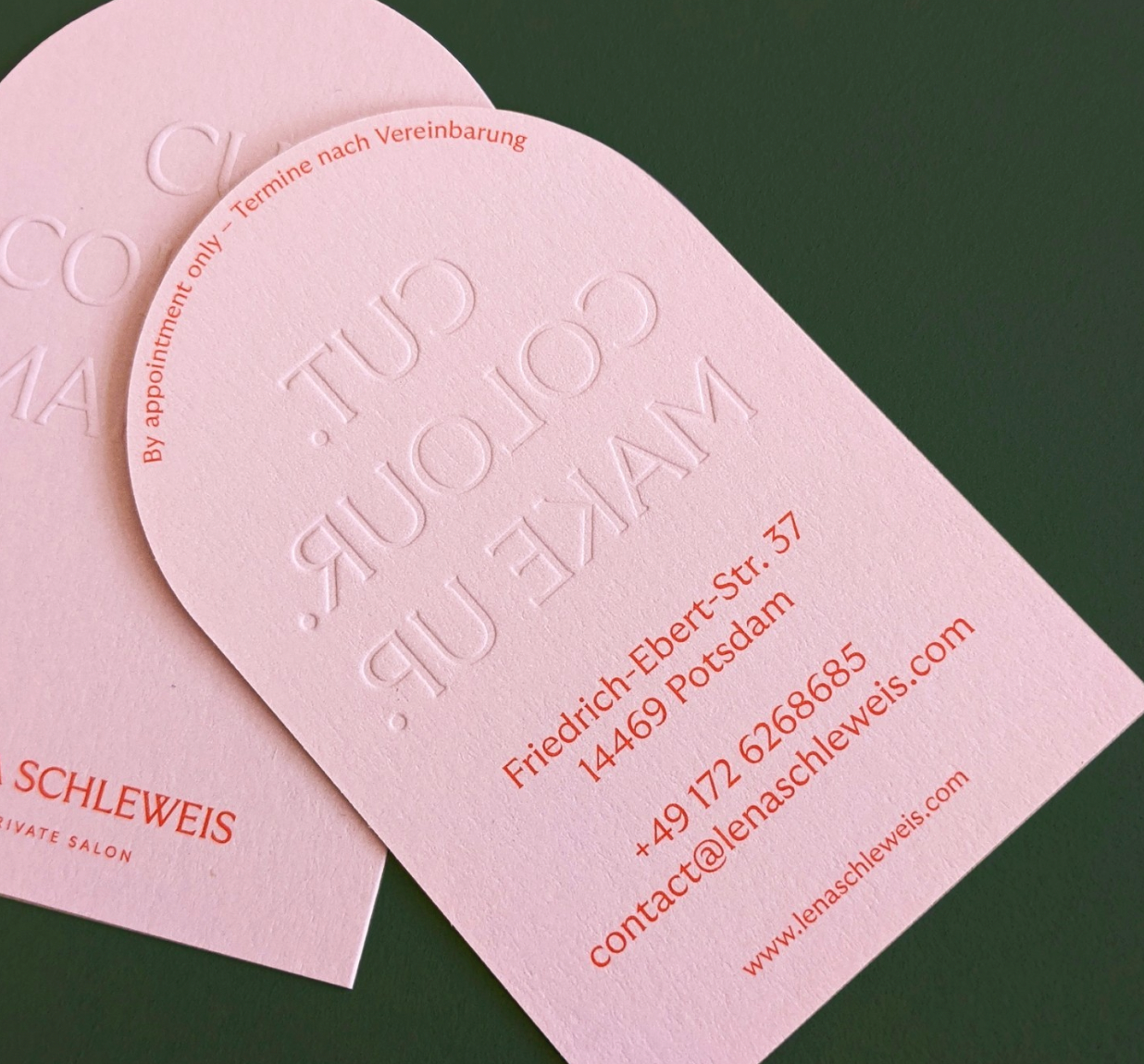 Pink arch-shaped on one side business card with red text.