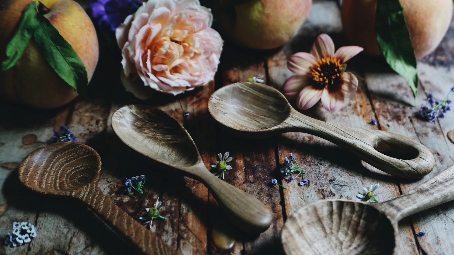 Handcrafted wooden spoons arranged among country farmhouse items and flowers