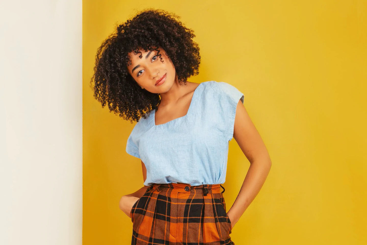 Person models a summer shirt and plaid pants against a bright yellow background