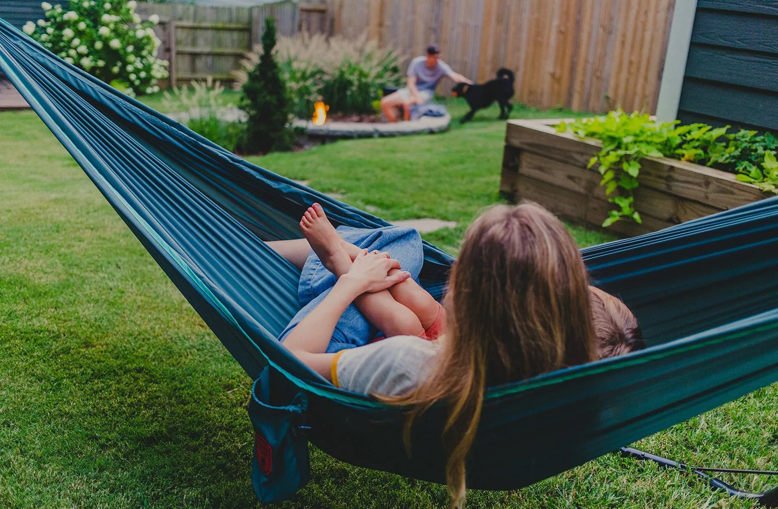 Person in a hammock stretched in a backyard