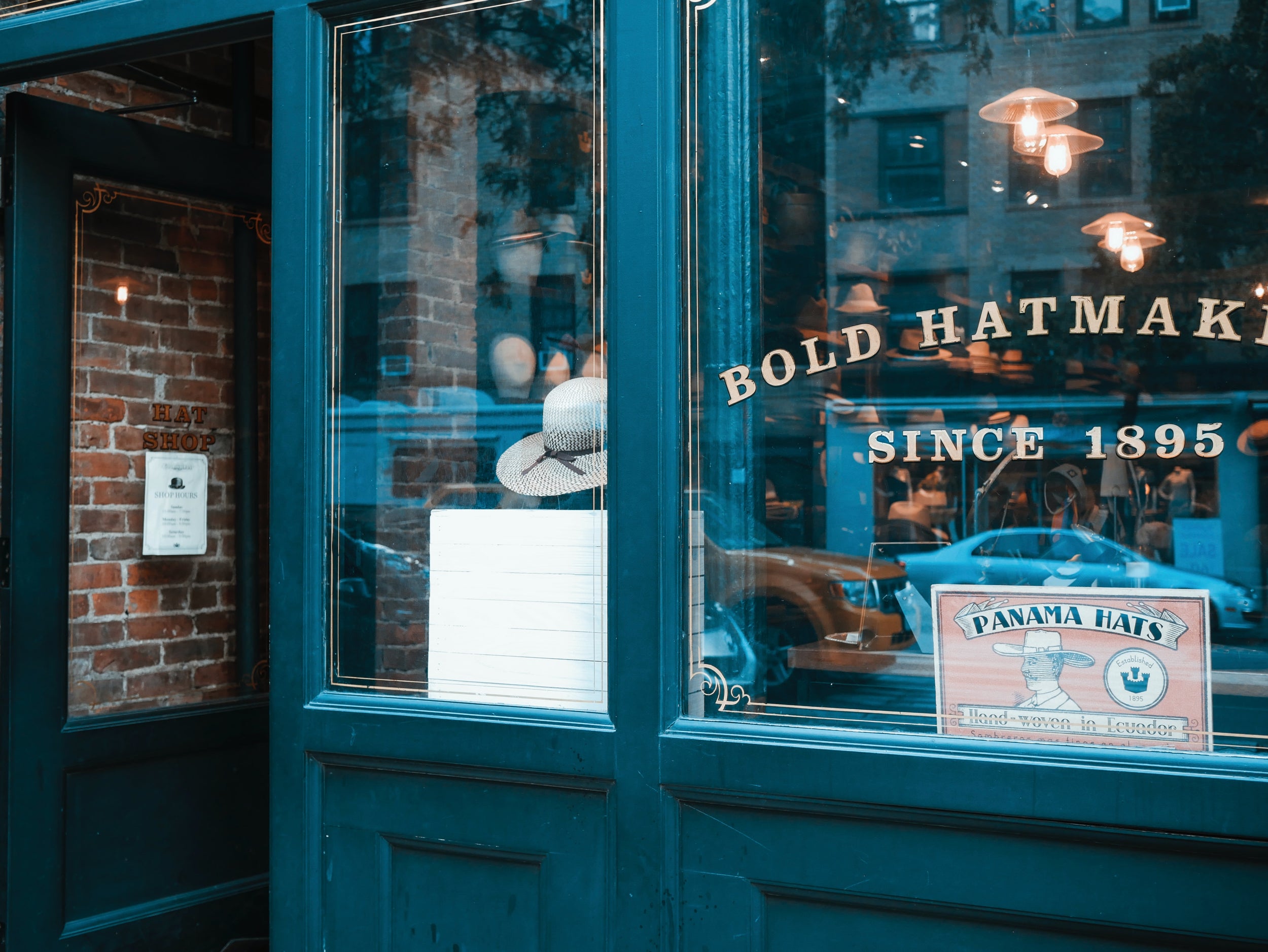 Storefront of a hat business. Window reads "bold hatmakers, since 1895"