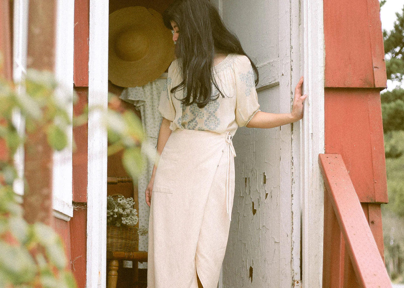 A woman stands in a doorway modelling a vintage dress