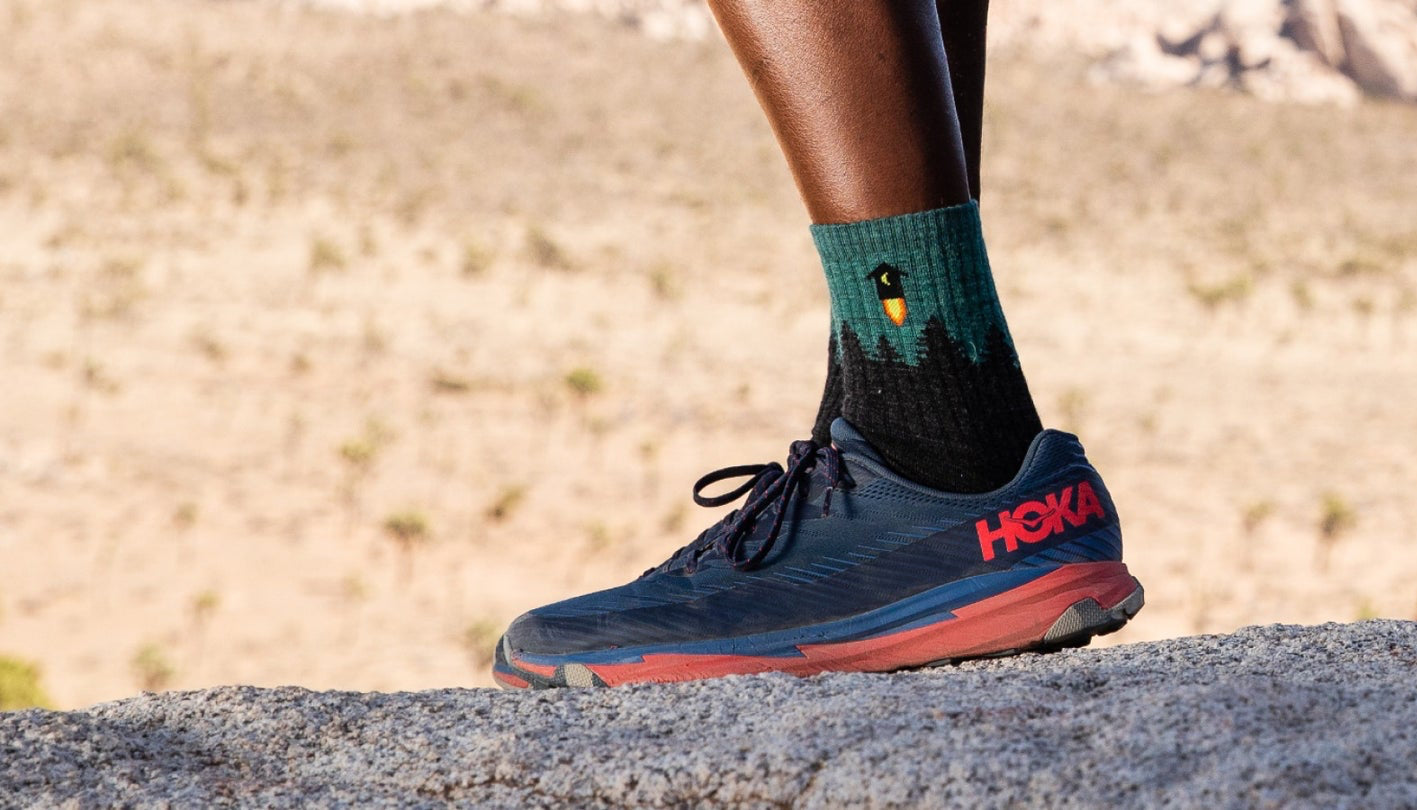 Close up of a person's foot wearing socks and sneakers in a desert setting