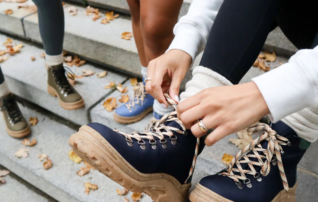 A person ties a pair of hiking boots