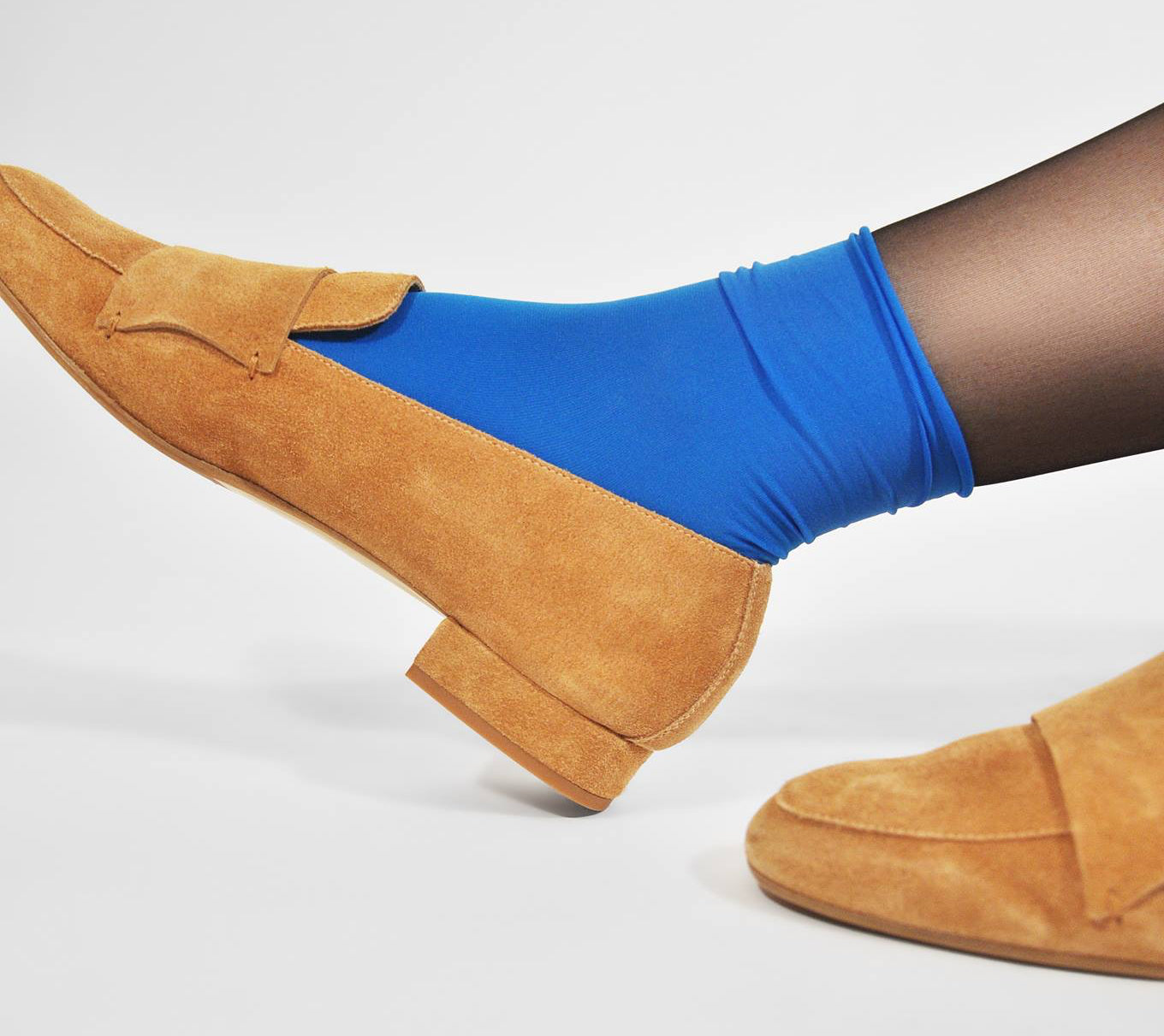 Close cropped shot of feet wearing blue socks and suede loafers