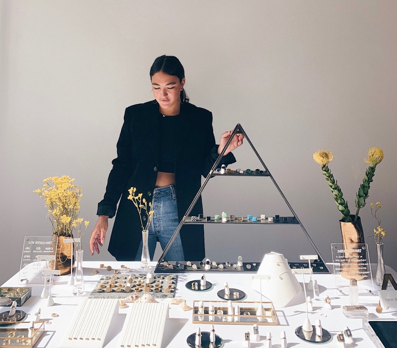 Artist Tarin Thomas standing behind a display table arranged with jewelry