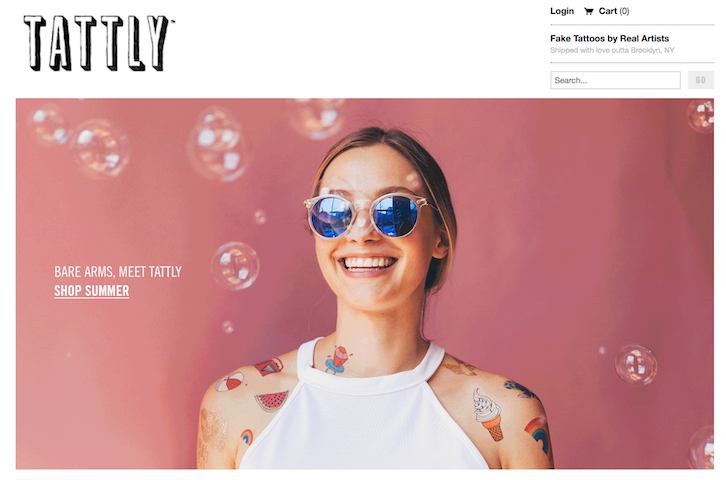A person wearing a white tank top and sunglasses modeling Tattly’s temporary tattoos.