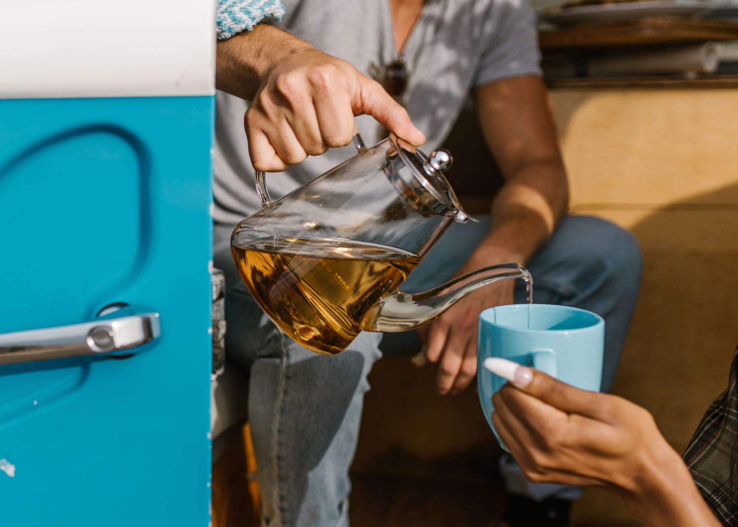 A person sitting in a camper pours tea into another person's mug