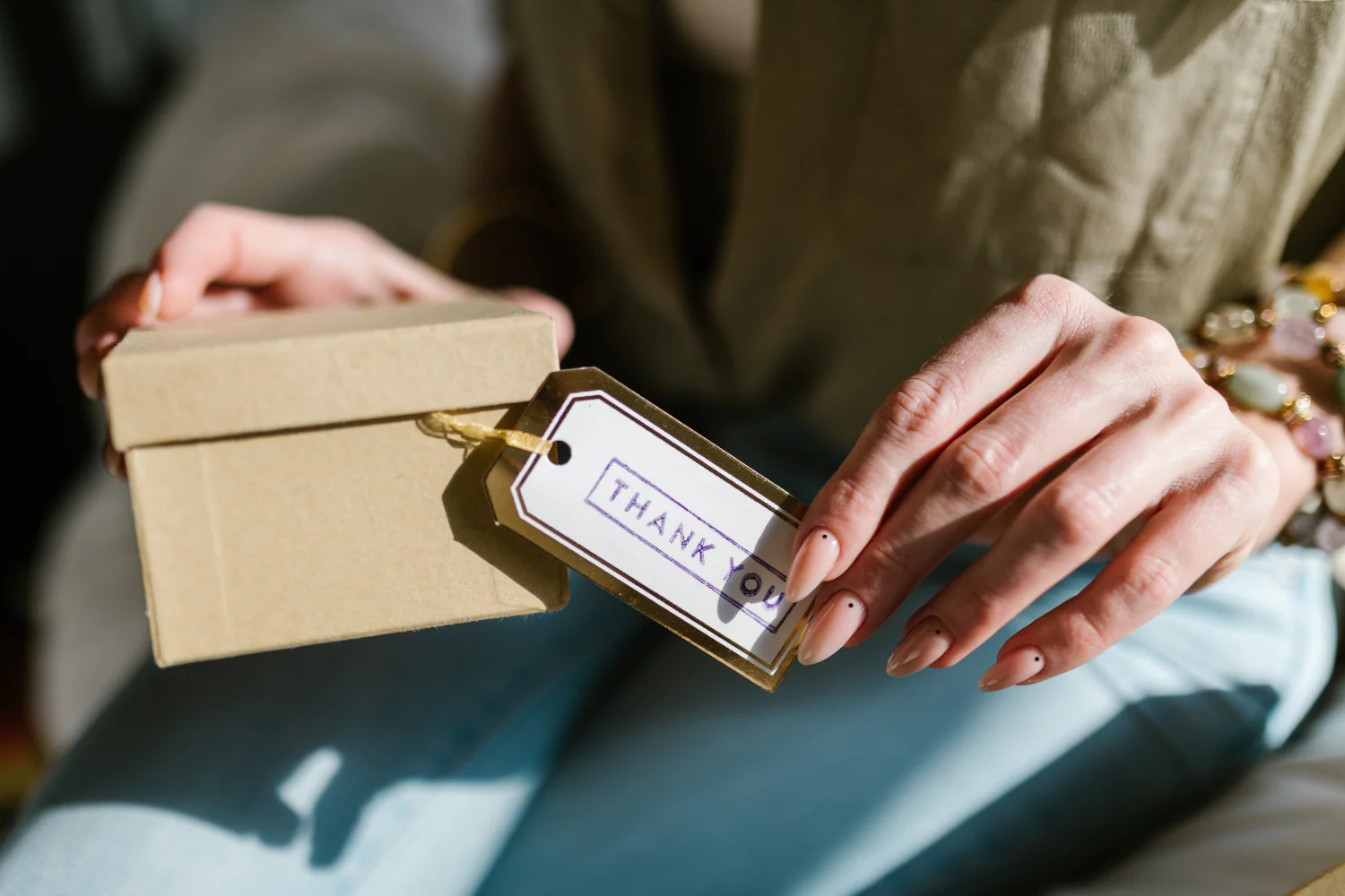 Woman holds a thank you tag attached to a box