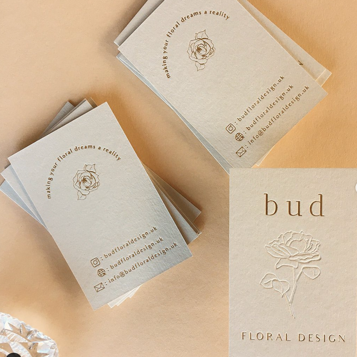 Neutral, minimalist business cards with an embossed rose and gold text.