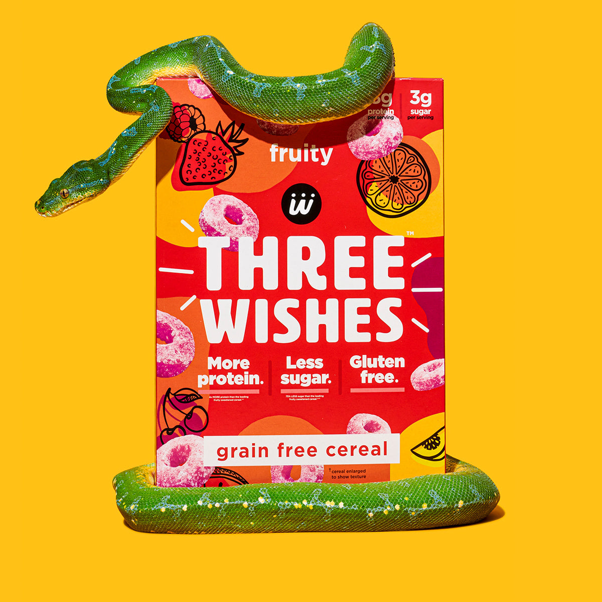 The fruity cereal by Three Wishes Cereal against a yellow background and wrapped by a stuffed animal snake. 