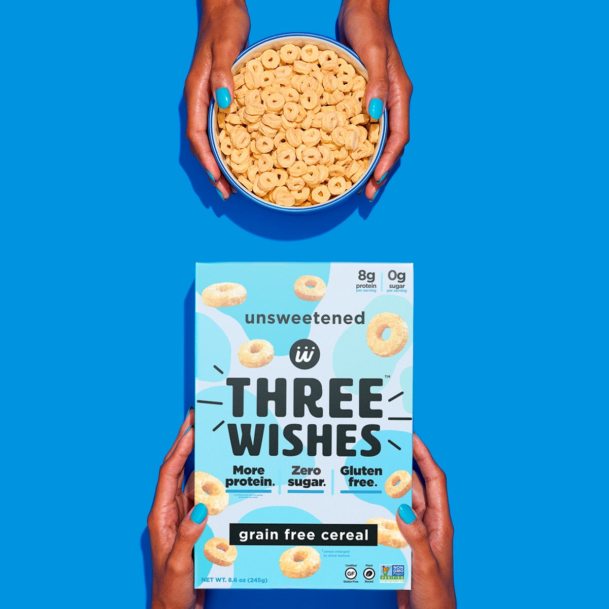 The unsweetened cereal by Three Wishes Creal held up by a pair of hands against a blue background. 